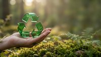 Hand holding green recycling symbol in natural forest environment with sunlight filtering through trees promoting environmental sustainability and eco-friendly practices.