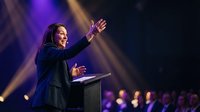Professional African American businesswoman giving passionate speech at podium with dramatic stage lighting and purple spotlights during corporate event.