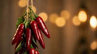 Fresh red chili peppers hanging on rope with warm bokeh lights background for cooking and culinary decoration projects.