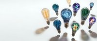 Creative lightbulbs with colorful patterns and textures floating above reaching hands on white background. Innovation and idea generation concept.