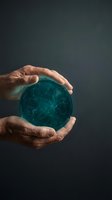 Mature male hands holding glowing teal digital sphere with network connections against dark background, representing technology innovation, data protection, and global connectivity for business concepts.