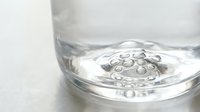 Clear water with air bubbles in glass container on white surface for hydration and refreshment concepts in clean minimalist style.