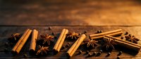 Cinnamon sticks and star anise spices arranged on rustic wooden surface for cooking, baking, culinary and food styling projects.