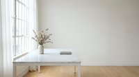 Minimalist white desk workspace with dried flowers in vase and notebook by large window, clean modern interior design for home office productivity.
