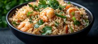 Aromatic shrimp fried rice garnished with fresh herbs in black bowl, close up view. Asian cuisine with tender seafood, fluffy grains and vibrant vegetables.