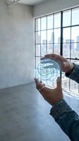 Hands holding a glowing holographic spiral orb in a modern loft space, symbolizing futuristic technology, energy, and digital innovation.