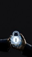 Hands in dark gloves holding glowing padlock with keyhole against black background, symbolizing security, protection, and data safety for business and technology concepts.