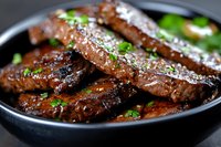 Juicy grilled beef short ribs glazed with sweet and savory Asian-style marinade, garnished with fresh herbs and sesame seeds served in black ceramic bowl.
