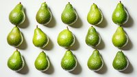 Fresh green avocados arranged in neat rows on white background, showing textured skin and teardrop shapes, isolated for easy design use in food photography.