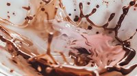 Chocolate milk splash creating dynamic crown shape with droplets and swirls in rich brown liquid motion against light background for beverage advertising.
