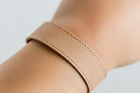 Beige elastic compression band wrapped around wrist, medical support garment for injury prevention and pain relief during sports and rehabilitation.