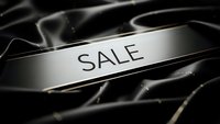 Elegant silver metallic ribbon with SALE text on dark flowing fabric background for luxury retail marketing and promotional campaigns.