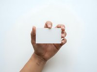 Male hand holding blank white card against neutral background, suitable for business cards, promotional materials, advertising campaigns, and marketing presentations.