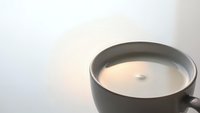 Steaming hot coffee cup with creamy milk on white background creating warm morning atmosphere for cafe and beverage concepts.