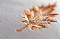 Delicate maple leaf shape covered in shimmering copper and gold glitter on light textured background, creating elegant autumn seasonal decor element.