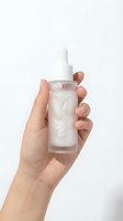 Female hand holding frosted glass dropper bottle with white serum on clean background for skincare and beauty product presentation.