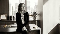 Professional businesswoman sitting on desk in modern office workspace with city view background for corporate presentations and career success concepts.