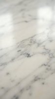 White marble surface with natural gray veining and soft lighting creates elegant backdrop for luxury product photography and interior design projects.