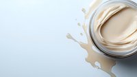 Creamy beige foundation makeup in glass jar with liquid splash and drops on white background for cosmetic advertising and beauty product design.