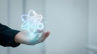 Caucasian male hand in dark business suit holding glowing atom symbol with orbital electrons, representing science, technology, research, innovation, and nuclear energy concepts for corporate use.