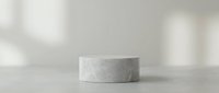 Minimalist concrete cylinder podium on neutral surface with soft natural lighting and shadows for product display and presentation purposes.