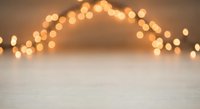 Warm golden bokeh lights creating dreamy atmosphere above white textured surface for holiday decorations, festive backgrounds and seasonal design projects.