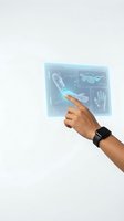 Male hand with dark skin tone wearing smartwatch interacting with holographic medical scan display showing skeletal and anatomical data.