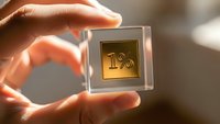 Hand holding transparent cube with golden one percent symbol for financial concepts and interest rates in warm lighting.