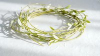 Natural green vine wreath with delicate white leaves on marble surface for spring decoration, wedding centerpiece, rustic home decor and craft projects.