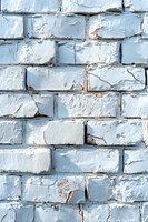 Old brick wall painted in light blue with peeling paint and weathered texture showing rough surface and irregular patterns. Suitable for urban backgrounds.