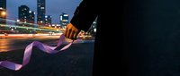 Hand holding purple ribbon with city lights and urban skyline at night, suitable for business, creativity, and innovation concepts.