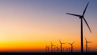 Wind turbines silhouetted against vibrant sunset sky generating clean renewable energy for sustainable power production and environmental conservation.