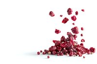 Freeze-dried red raspberries scattered and piled on white background, showing natural texture and vibrant color. Isolated healthy snack for food packaging design.