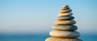 Balanced stack of smooth river stones creating zen meditation tower against serene ocean backdrop for wellness and mindfulness concepts.