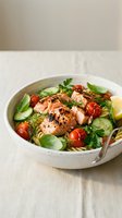 Grilled salmon fillet with fresh herbs, cherry tomatoes and greens in white bowl on linen tablecloth for healthy dining and Mediterranean cuisine recipes.