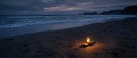 Cozy campfire burning on sandy beach at twilight with ocean waves and dramatic purple sky creating peaceful evening atmosphere for relaxation and romance.