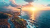 Wind turbine on coastal cliff with winding road along ocean shore at dramatic sunset. Aerial view of renewable energy and sustainable infrastructure.