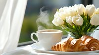 Fresh baked croissant and steaming coffee cup on windowsill with white tulips bouquet in morning light, cozy breakfast scene with natural window view.