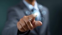 Professional in suit pointing at glowing digital interface with floating business icons, demonstrating modern technology interaction and smart business solutions.
