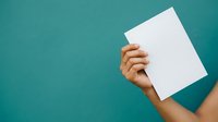 Hand holding blank white paper sheet against teal background. Suitable for advertising, marketing campaigns, presentations, and promotional materials.