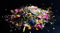 Aromatic loose leaf herbal tea blend with dried rose petals, chamomile flowers, and lavender buds scattered on dark background with golden sparkles.