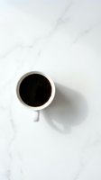 White coffee cup with black coffee on marble surface from above for morning beverage and cafe branding projects.