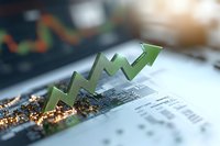 Green arrow graph showing upward market trend on financial document with electronic circuit board background, representing growth and success in business.