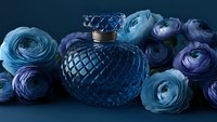 Elegant blue glass perfume bottle with diamond pattern surrounded by turquoise and purple ranunculus flowers on dark background, luxury fragrance concept.