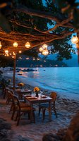 Romantic beachfront restaurant at twilight with hanging lanterns illuminating wooden tables on sand, ocean waves and distant lights creating magical evening ambiance.