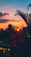 Dramatic silhouette of palm fronds and ferns against vibrant orange and pink sunset sky with bokeh lights creating magical tropical atmosphere.