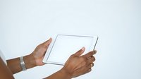 Hands of a middle-aged man with medium brown skin tone holding and using a tablet device against a white background for technology and business concepts.
