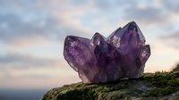 Amethyst crystal cluster on mossy rock with dramatic sky, showcasing natural purple gemstone beauty for wellness and spiritual themes.
