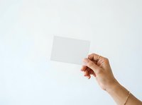 Hand holding blank white card isolated on light background, ready for design mockups, branding presentations, business cards, invitations, or promotional materials.