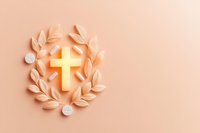 Christian cross with laurel wreath and medical pills on pastel peach background, faith and healthcare concept with copy space.